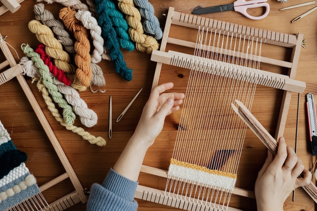 Mani al lavoro su un telaio artigianale come simbolo di autenticità, competenza e lavoro reale